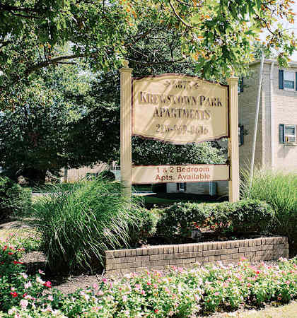a building with a sign in front of a garden at Krewstown Park Apartments, Philadelphia