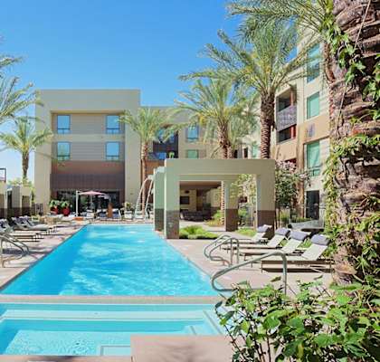 A pool surrounded by palm trees and sun loungers at Audere Apartments, Phoenix, AZ, 85016