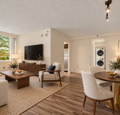 A living room with a white couch, a coffee table, and a television.