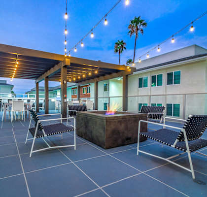 A patio with chairs and a fire pit under string lights at Bixby Hill Apartments in Long Beach, CA, 90815