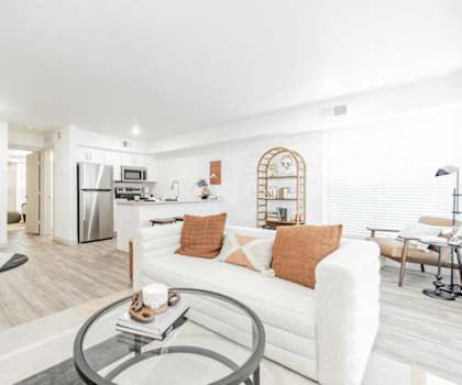A modern living room with a white couch and a glass coffee table.