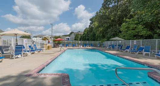 A large outdoor swimming pool with blue water and a red and white checkered border.