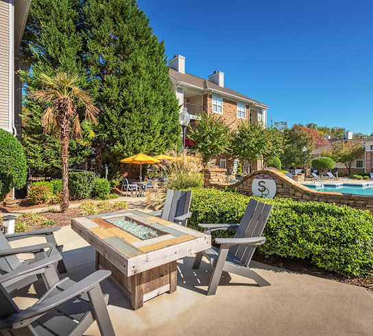 A patio with a table and chairs overlooking a pool.