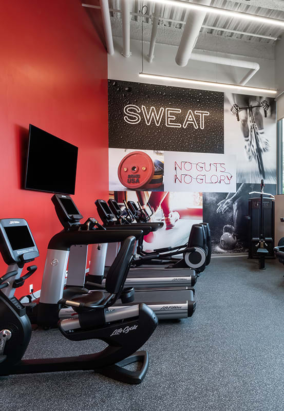 a gym with treadmills and other exercise equipment in a building with large windows