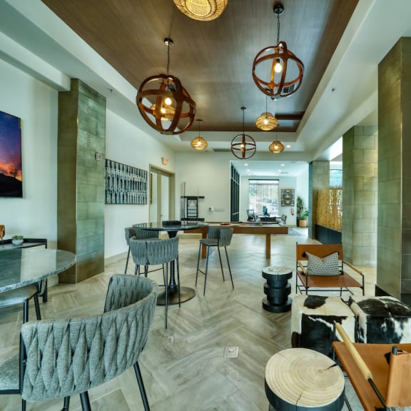 A modern living room with a fireplace and a pool table at Monument, Chandler, AZ