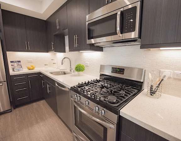 A modern kitchen with a stove top oven and microwave above it.