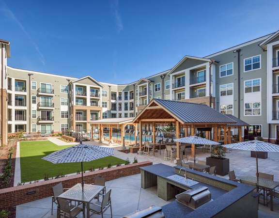 an outdoor patio with tables and umbrellas in front of an apartment complex