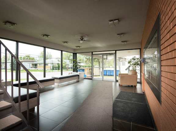 A long hallway with a staircase on the left and a bench on the right.