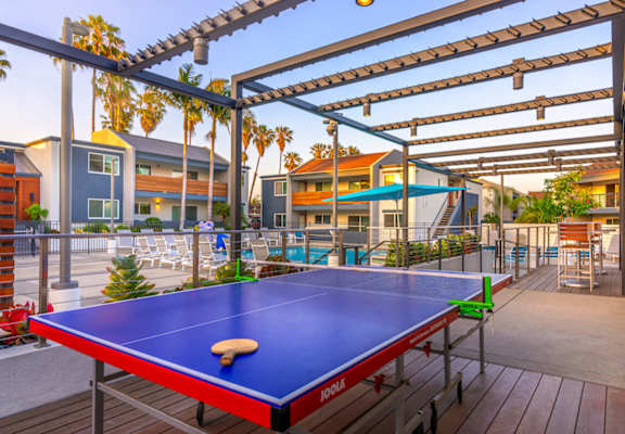 a blue ping pong table is set up on a wooden deck under a pergola