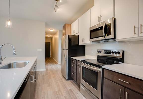 A kitchen with an oven, microwave, and island with a sink