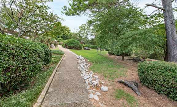 a path in a park with trees and bushes on either side