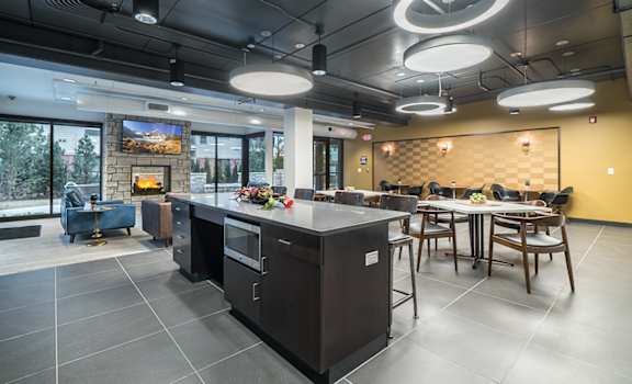 Large room with seating area and fireplace, kitchen, and many tables and seating areas