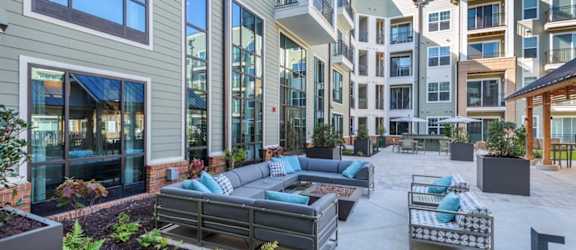an outdoor patio with tables and umbrellas in front of an apartment complex