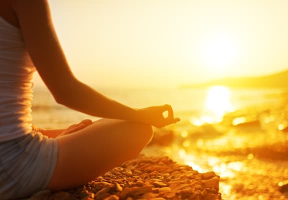 Lifestyle photo of woman at the beach meditating 