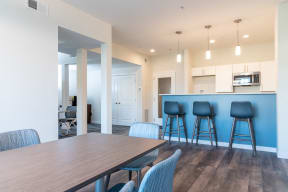 A dining room and kitchen with a table and bar stools