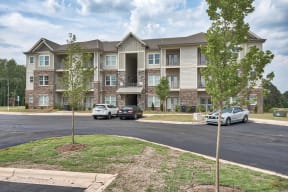 A large apartment complex with a parking lot in front.