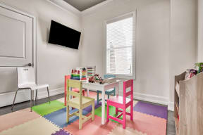 A room with a white table and chairs with a TV on the wall.