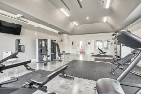 A spacious gym with a variety of equipment including treadmills, weights, and a television.
