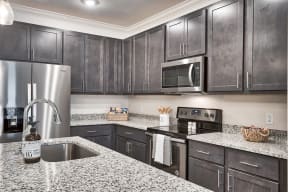 A kitchen with a granite counter top and stainless steel appliances.
