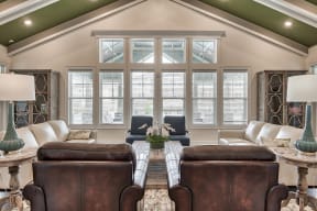 A living room with brown leather chairs and a large window.
