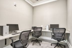 Three black chairs are arranged around a desk with a computer.