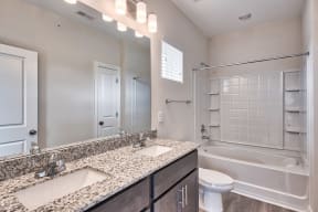 A bathroom with a granite countertop and a walk-in shower.