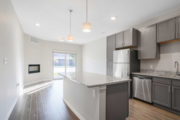 a open-concept kitchen with stainless steel appliances and granite counter tops next to a living room
