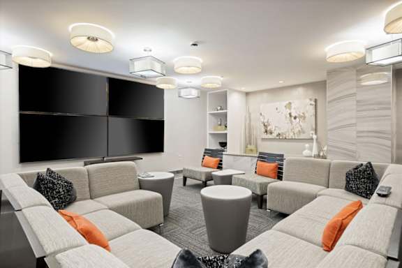 Comfortable resident lounge at Sky on Main with sectional seating, modern lighting, wall-mounted televisions, and gathering space.