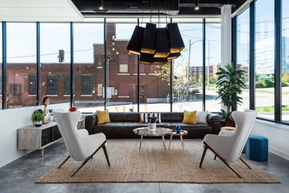 a living room with a leather couch and two white chairs