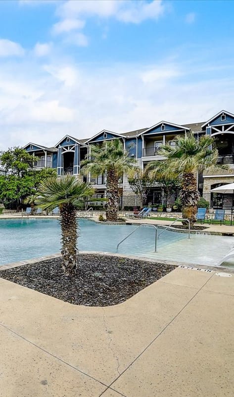 a swimming pool with palm trees and buildings in the background