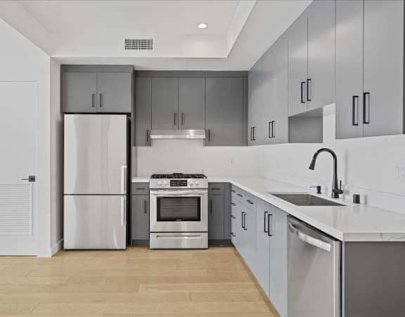 A modern kitchen with stainless steel appliances and wooden floors.