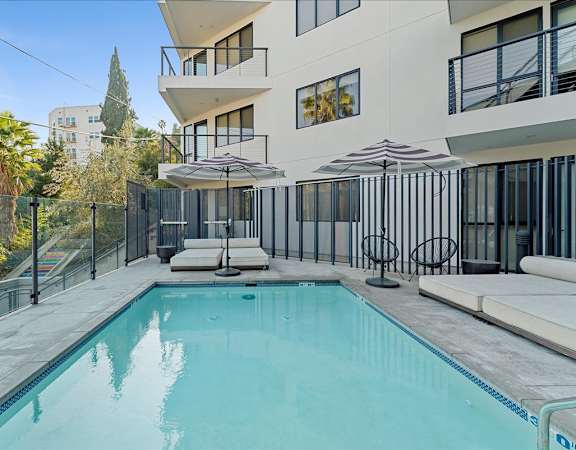 A swimming pool in a residential area with a white building in the background.