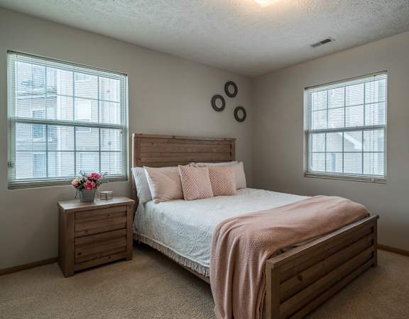 A bedroom with a bed, nightstand, and window.