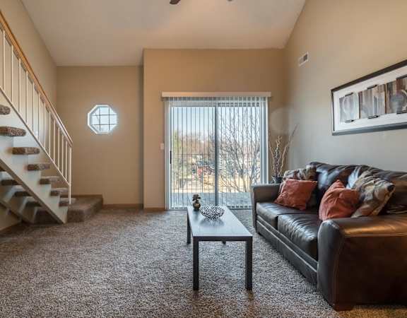 A living room with a couch, coffee table, and staircase.