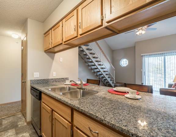A kitchen with granite countertops and wooden cabinets.
