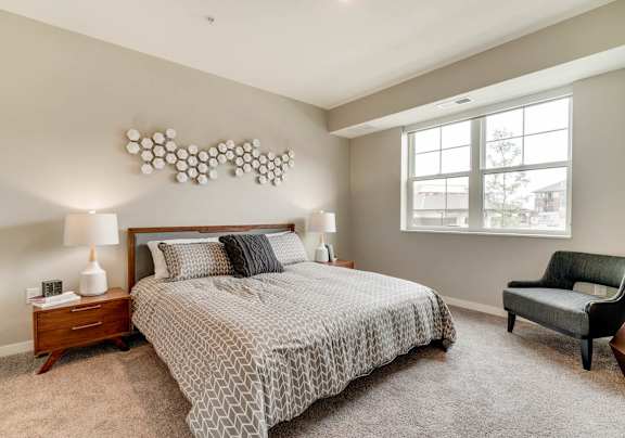 Spacious bedroom with carpet, natural light, and cherry wood furnishings.