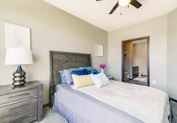 A bedroom with a bed, dresser, and ceiling fan.