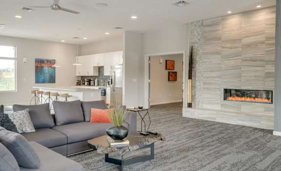 A modern clubhouse great room with a grey sofa and a fireplace.