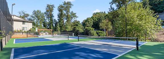 A tennis court with a green and blue surface surrounded by a fence.