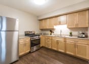 Thumbnail 3 of 39 - Kitchen with stainless steel appliances, light wood cabinetry, and plan flooring at Eden Commons, Chicago, IL