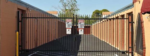 A black gate with a yellow post and a sign on it.