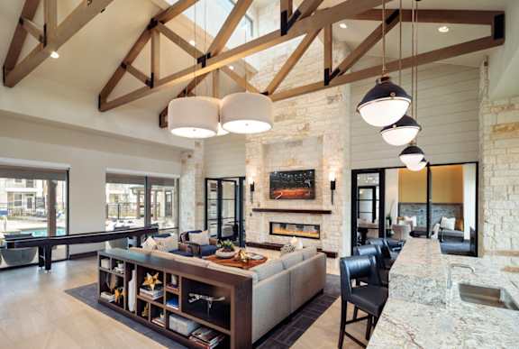 Elegant resident clubhouse featuring soaring ceilings, exposed wood beams, a modern fireplace, and comfortable lounge seating.