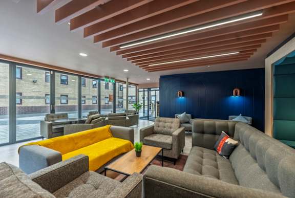 A modern lounge area with wooden slats on the ceiling and grey couches.