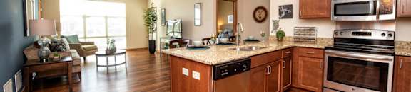 a kitchen and living room with wood flooring and stainless steel appliances