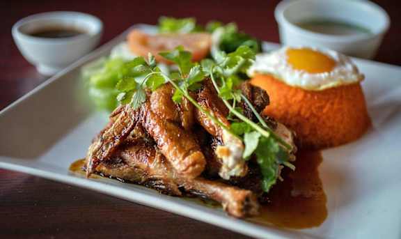 A plate of food with meat, a fried egg, and sauce.