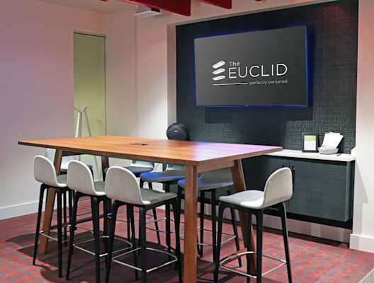 A conference room with a table, chairs and a screen displaying the Euclid logo. at The Elle on Lockwood Apartments, Webster Groves, MO, 63119