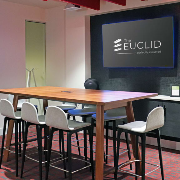 A conference room with a table, chairs and a screen displaying the Euclid logo. at The Elle on Lockwood Apartments, Webster Groves, MO, 63119