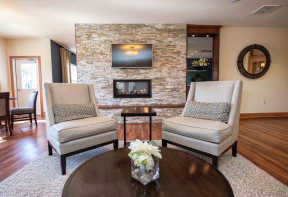 a living room with two chairs and a stone fireplace