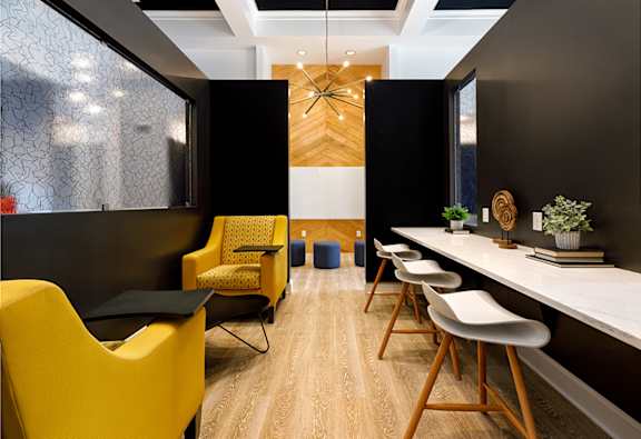 A modern office space with yellow chairs and a long white table.