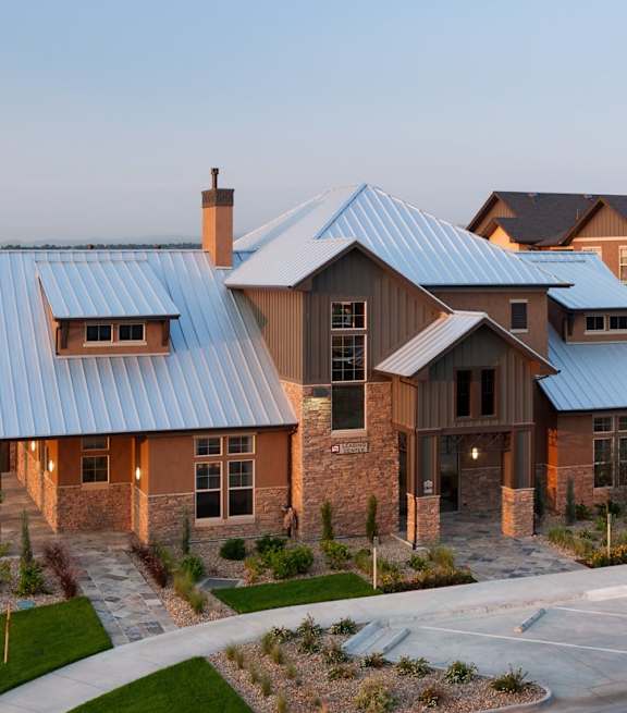 A large house with a blue roof and a stone wall.